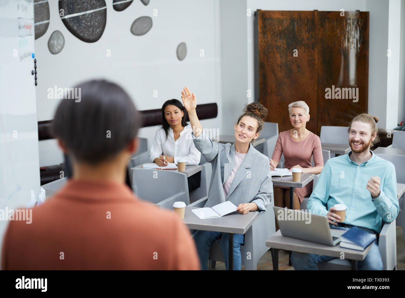 Weitwinkel Porträt des zeitgenössischen jungen Frau Hand in der Klasse mit einer Gruppe von Studenten mit Vortrag, Lehrer Sicht Stockfoto