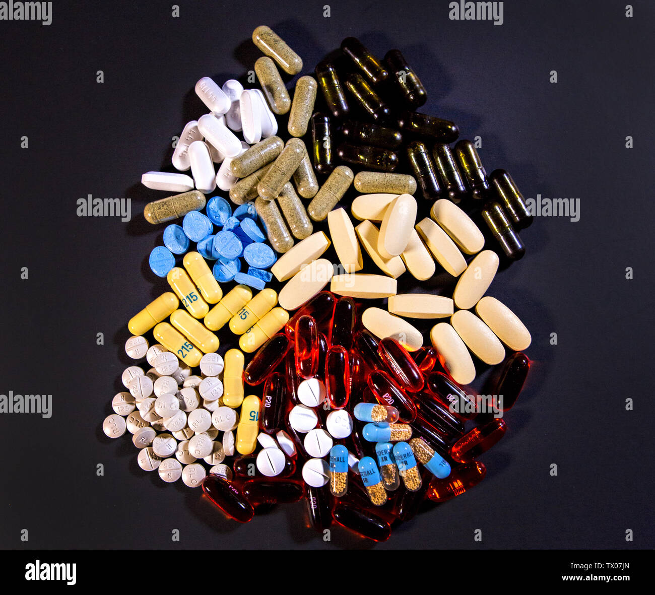 Ein bunter Haufen von Pillen sitzt auf einem Schwarzen Tisch. Stockfoto