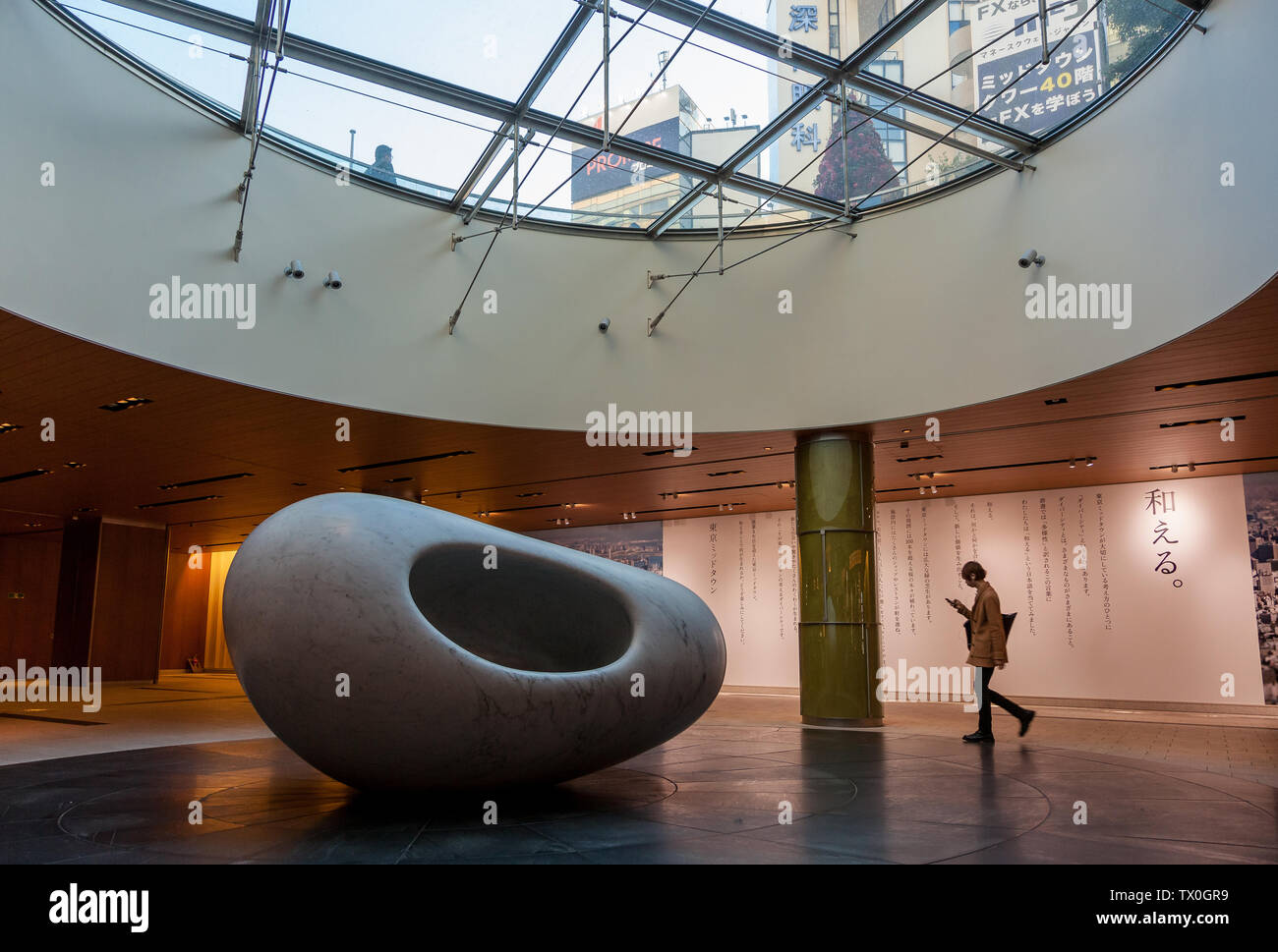 Eine Frau geht an einer modernen Skulptur in einem unterirdischen Einkaufszentrum im Einkaufs- und Wohnkomplex Tokyo Midtown in Roppongi, Tokio, Japan, vorbei. Stockfoto
