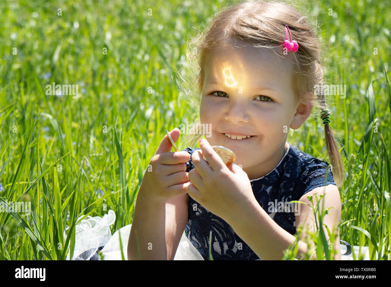 Kleines Mädchen mit einem bitcoin cryptocurrency Münze in Händen. Ein Kind spielt mit Goldmünzen sitzen auf dem Gras Stockfoto