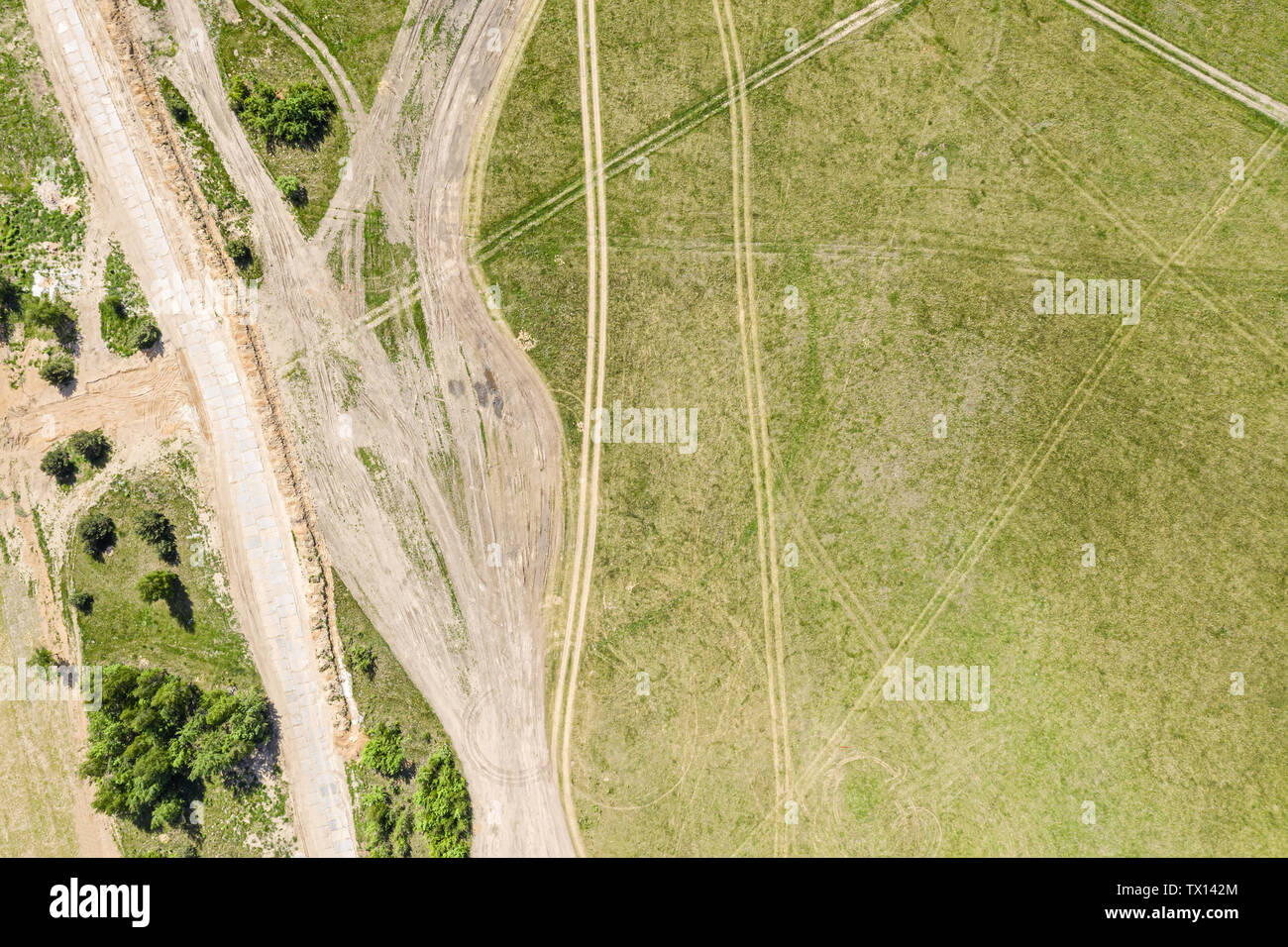 Fliegen über leere Landstraße durch weite Wiesen an einem sonnigen Sommertag Stockfoto