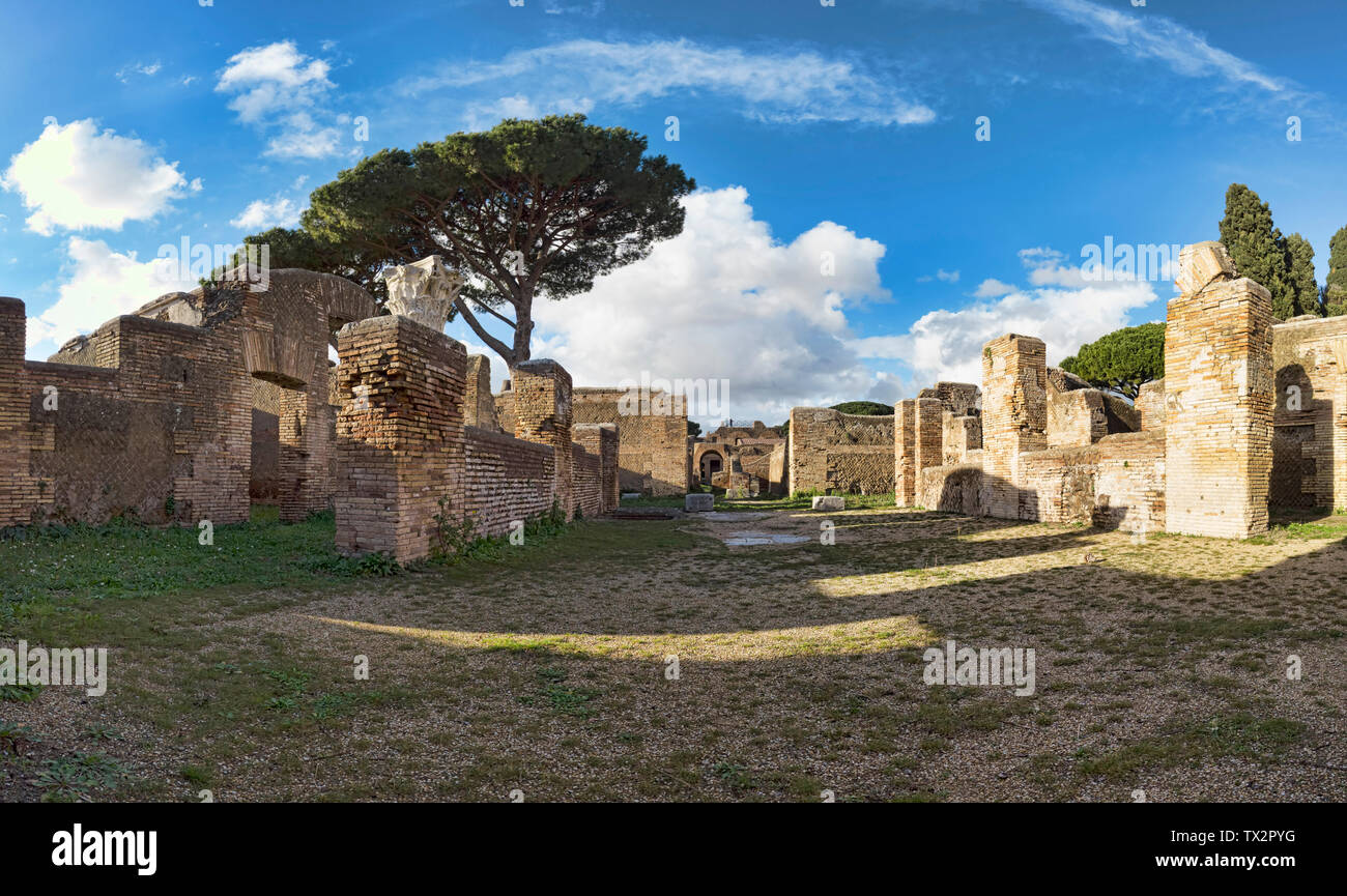 Panoramablick in die archäologischen Ausgrabungen von römischen Dorf von Ostia Antica, mit mit Ruinen der antiken Gebäude mit Rundbögen und geschnitzten Stockfoto