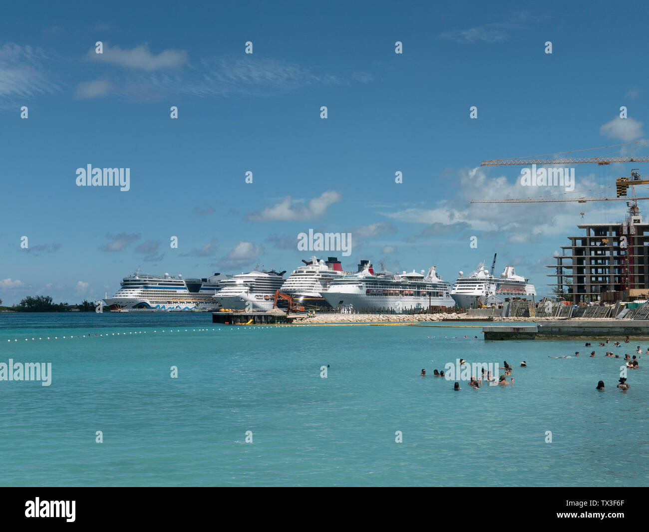 Touristen schwimmen im sonnigen Ozean mit Kreuzfahrtschiffen im Hintergrund, Nassau, Bahamas Stockfoto