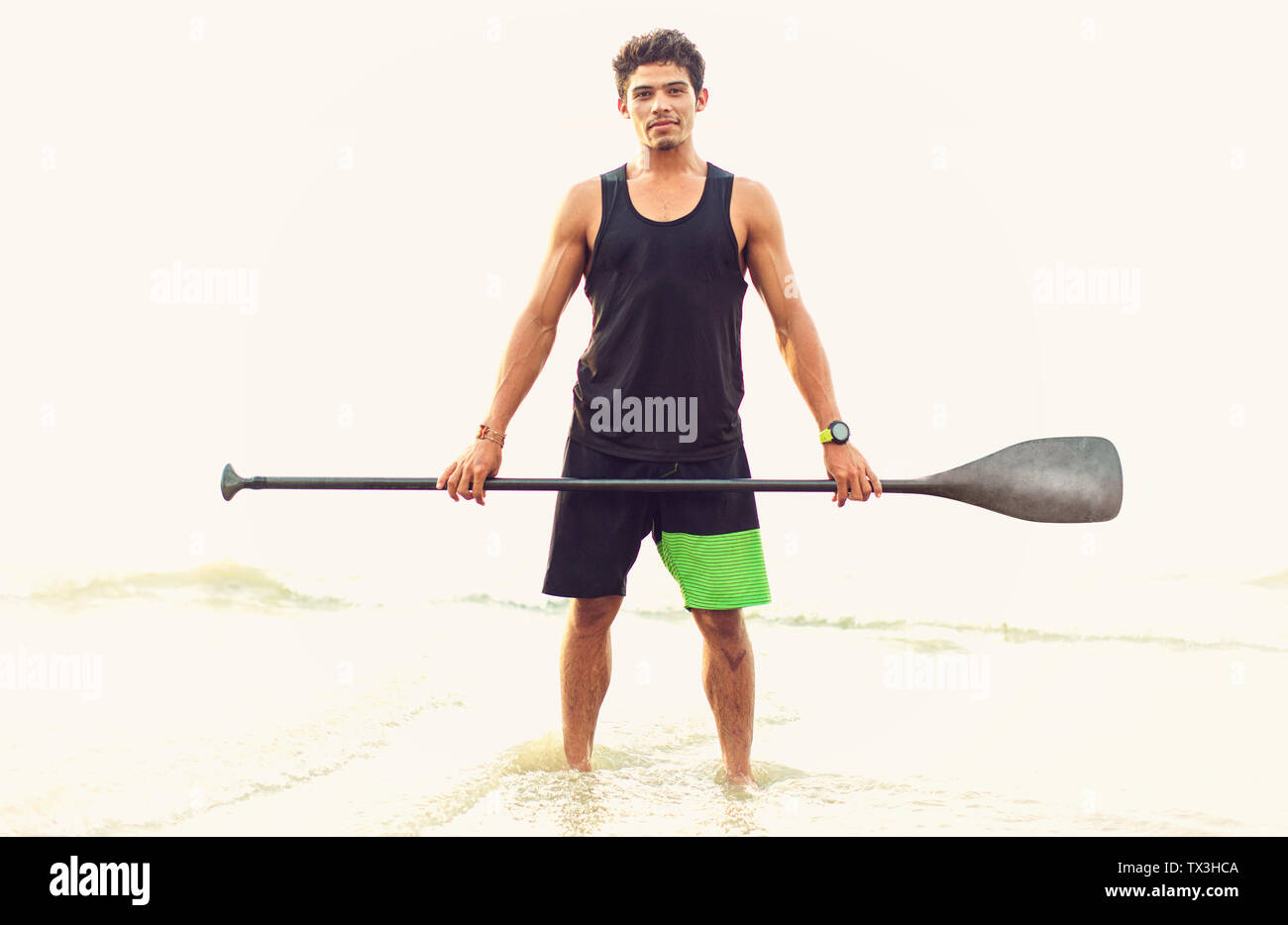 Portrait selbstbewussten jungen Mann mit Ruder im Ocean Surf Stockfoto
