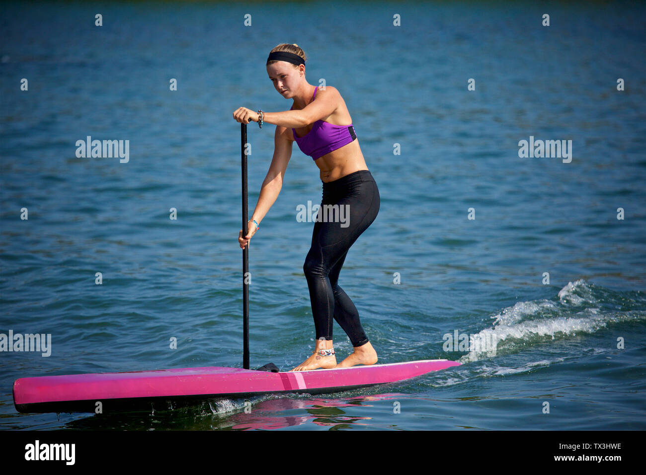 Junge Frau paddleboarding an sonnigen Ozean Stockfoto