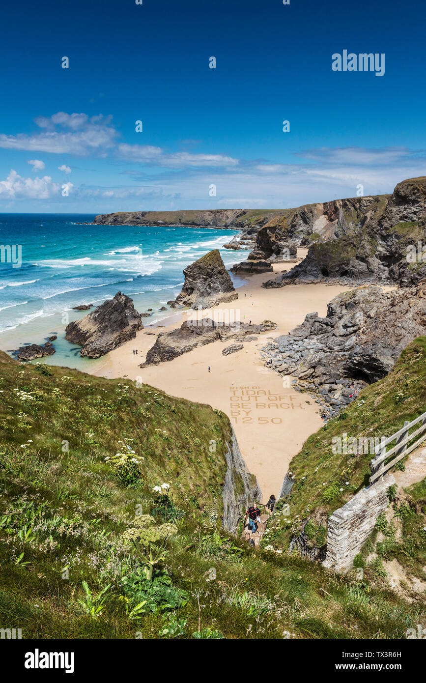 Touristen, die auf der Aussichtsplattform mit Blick auf die wilde, schroffe spektakuläre Bedruthan Steps auf der nördlichen Küste von Cornwall. Stockfoto