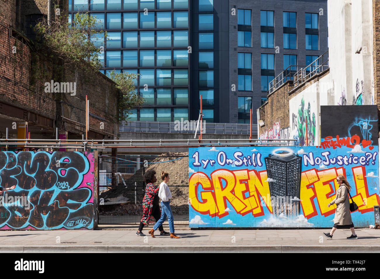 Ein Blick auf die Straße von Shoreditch High Street in London mit Graffiti auf den architektonischen Werbetafeln mit der Meldung Grenfell 1 Jahr auf und noch immer keine Gerechtigkeit. Stockfoto