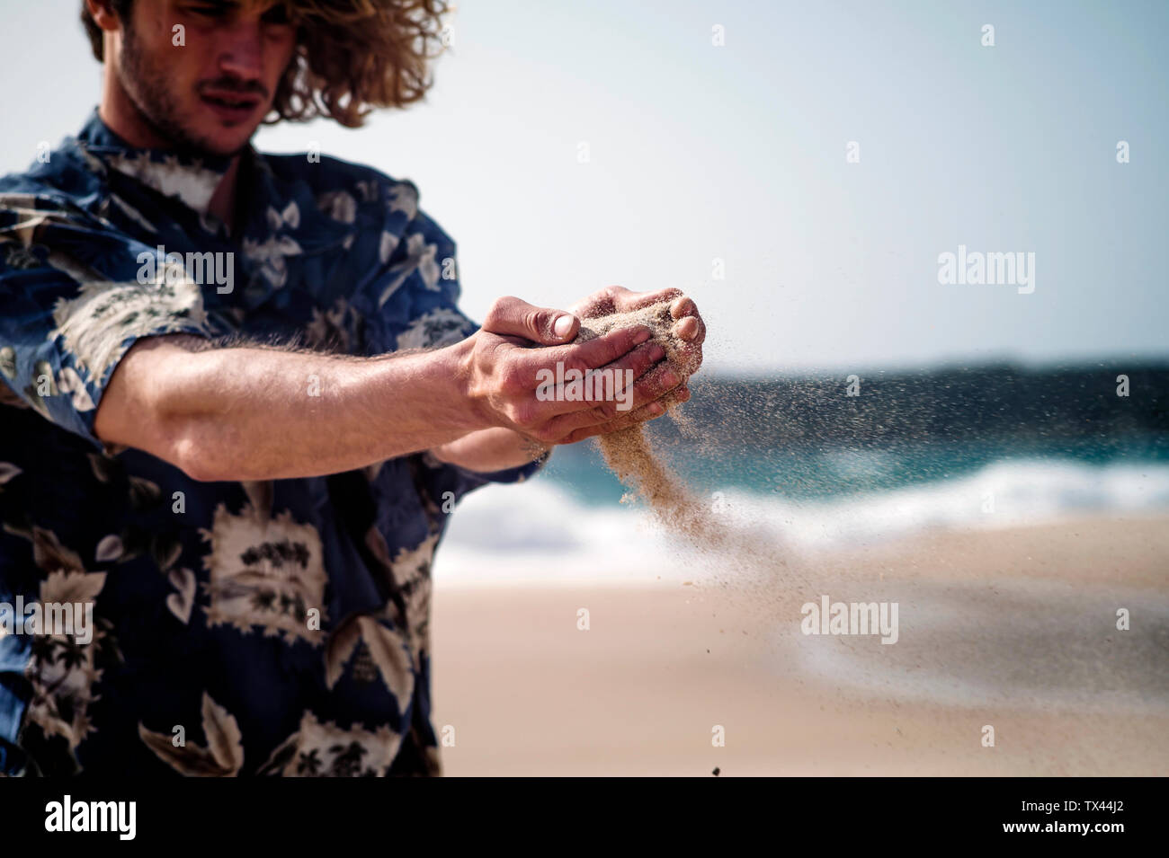 Mann am Strand rieselnde Sand durch seine Hände Stockfoto