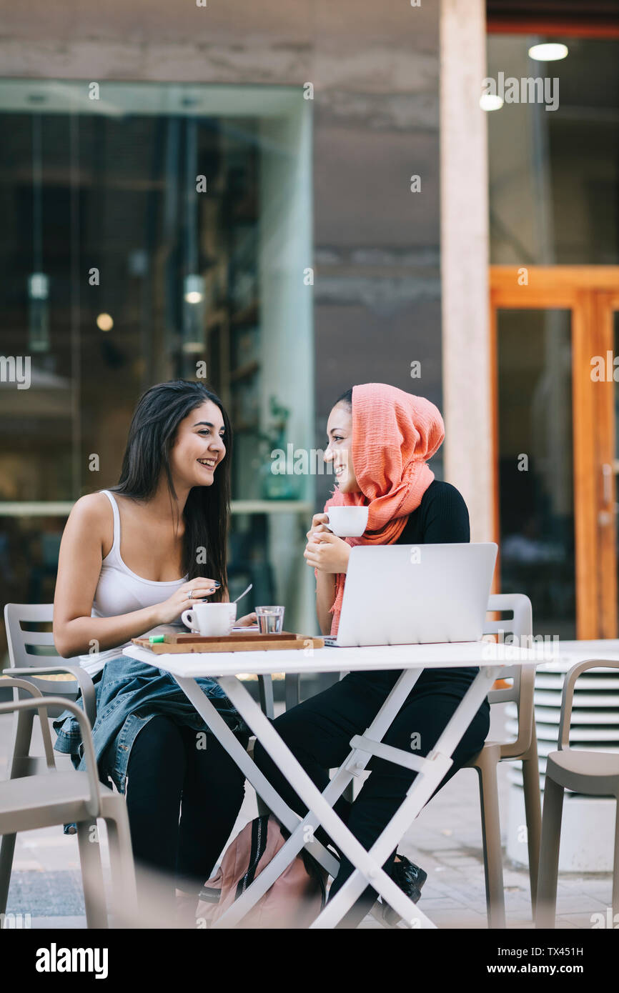 Zwei glückliche Freunde sitzen zusammen in einem Cafe mit Laptop Stockfoto