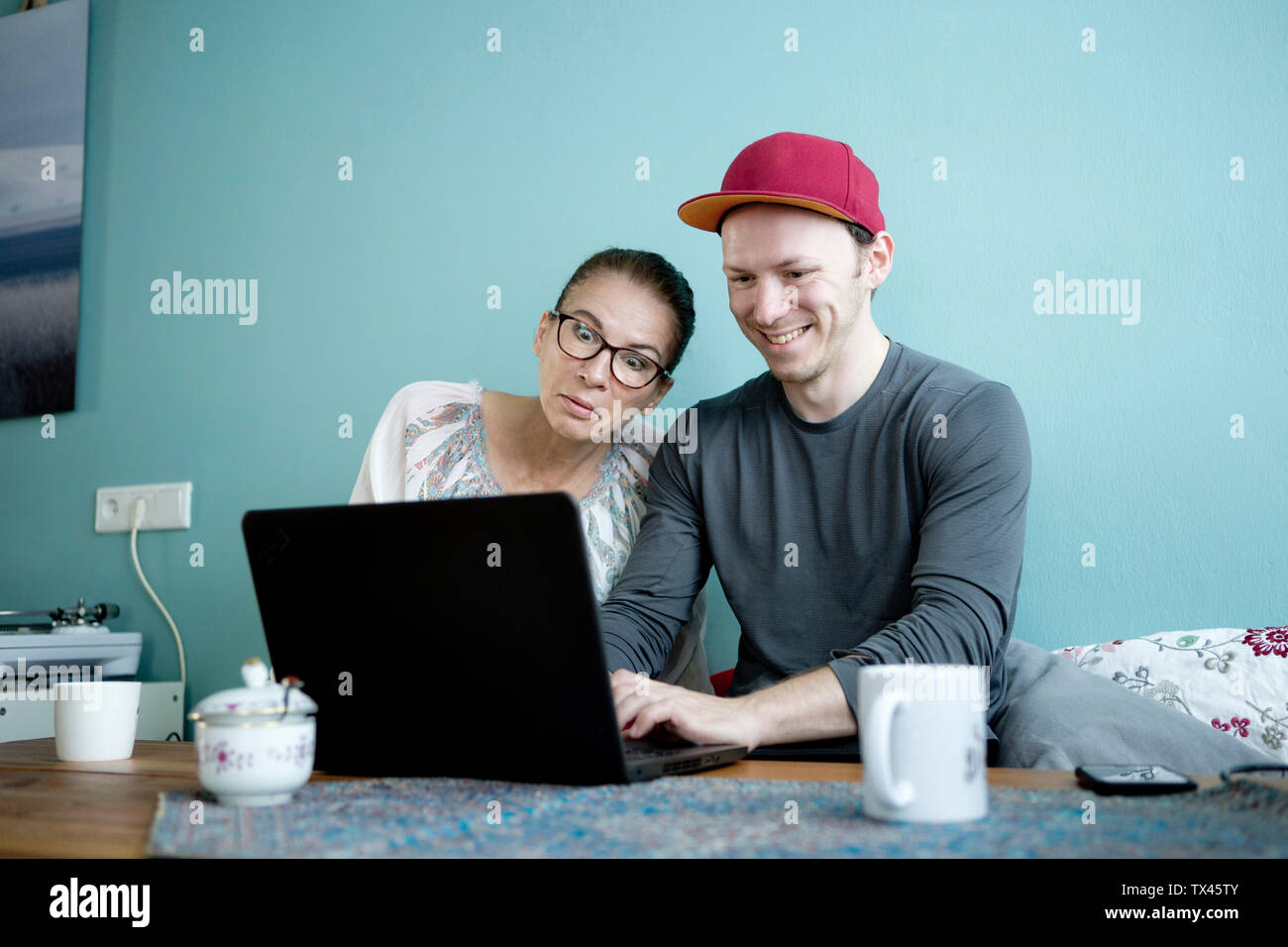 Mutter und Sohn am Küchentisch sitzen, mit Laptop Stockfoto