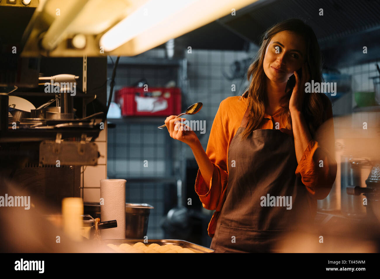 Junge Frau mit Handy im Restaurant Küche Stockfoto