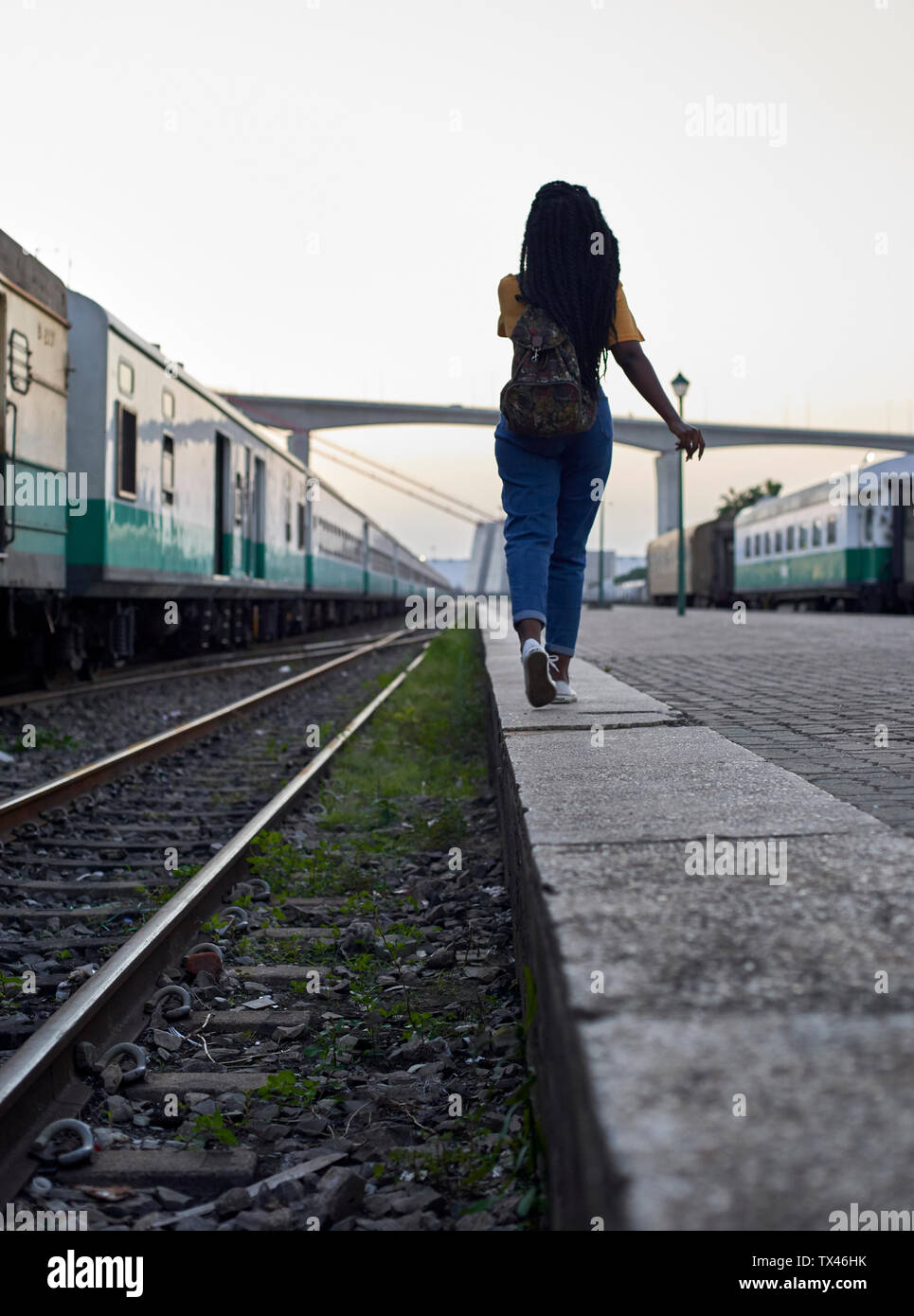 Ansicht der Rückseite des Junge Frau wandern am Rand der Rampe am Bahnhof Stockfoto