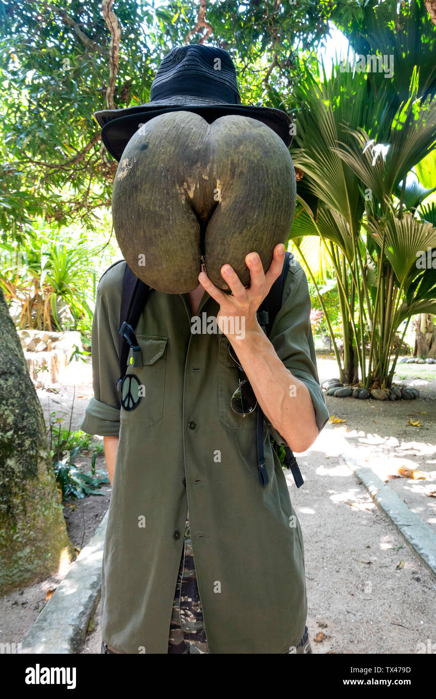 Seychellen, Mann sein Gesicht versteckt hinter riesigen Saatgut von Coco de Mer Stockfoto