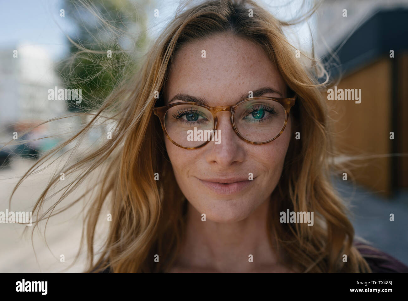 Portrait von selbstbewussten jungen Frau mit Brille und windgepeitschten Haar Stockfoto