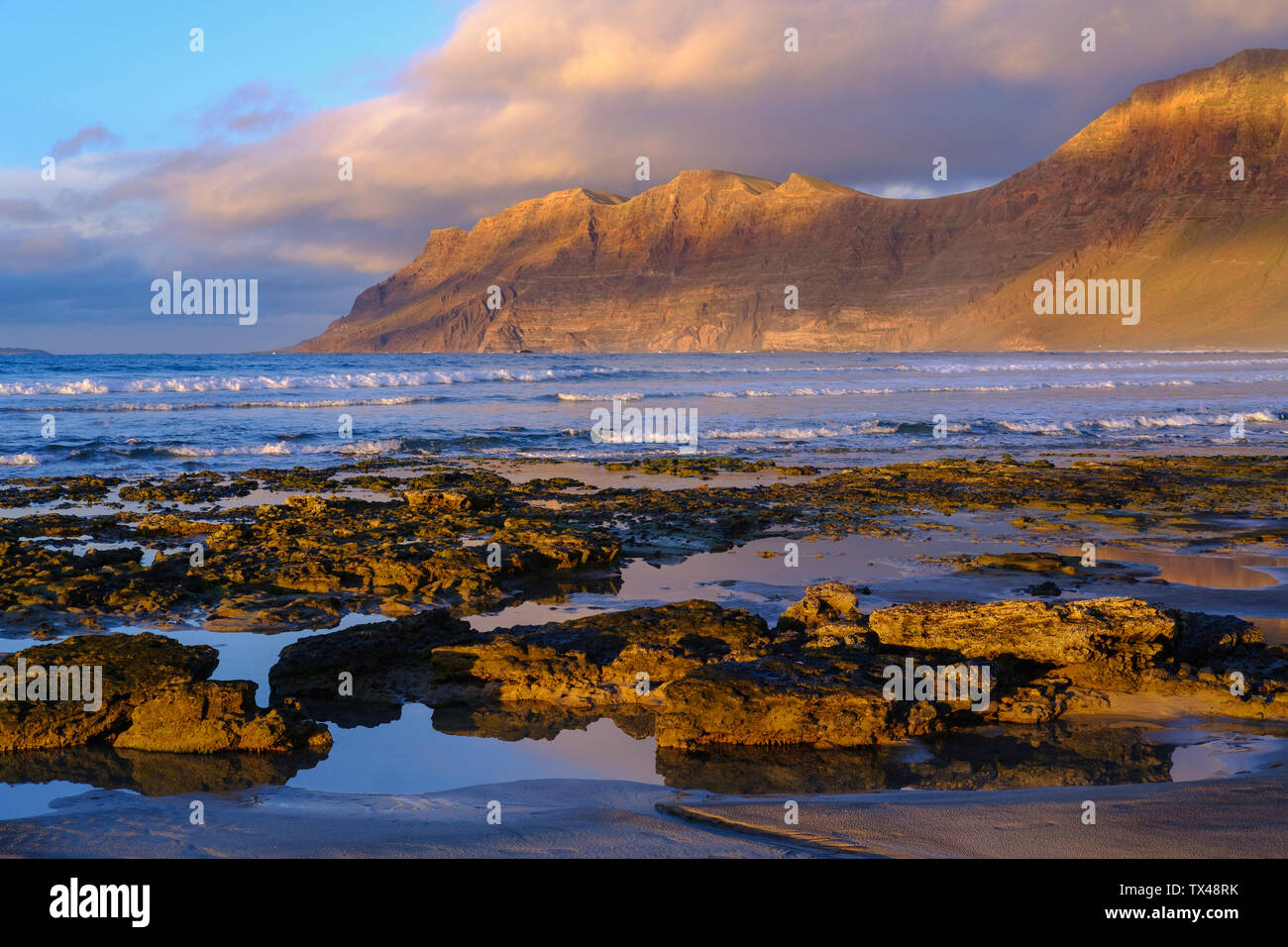 Spanien, Kanarische Inseln, Lanzarote, Caleta de Famara, Strand und Risco de Famara im Hintergrund Stockfoto