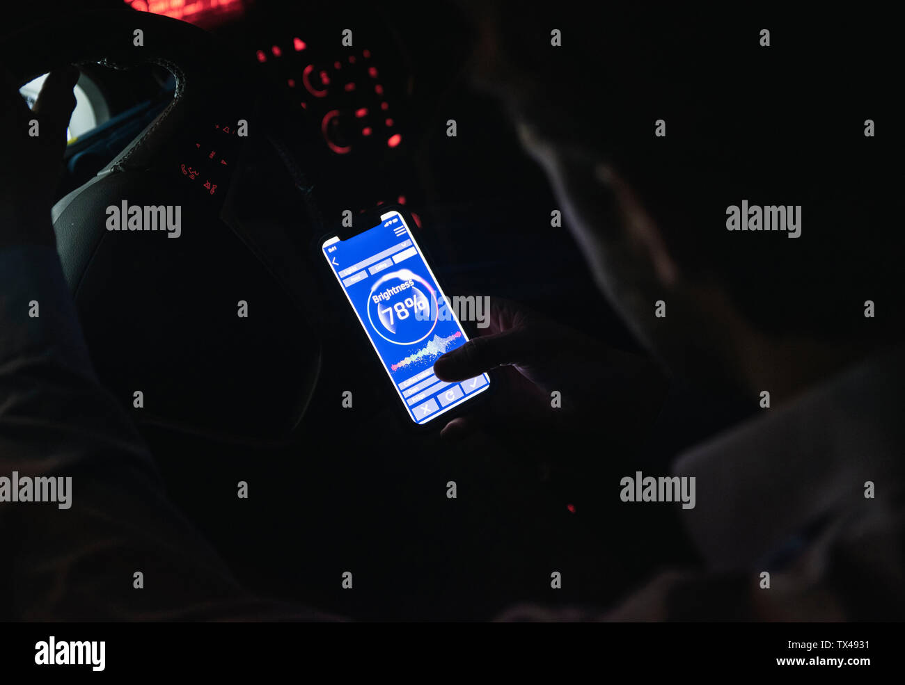 Close-up des jungen Mannes Anpassen der Helligkeit der Handy im Auto in der Nacht Stockfoto