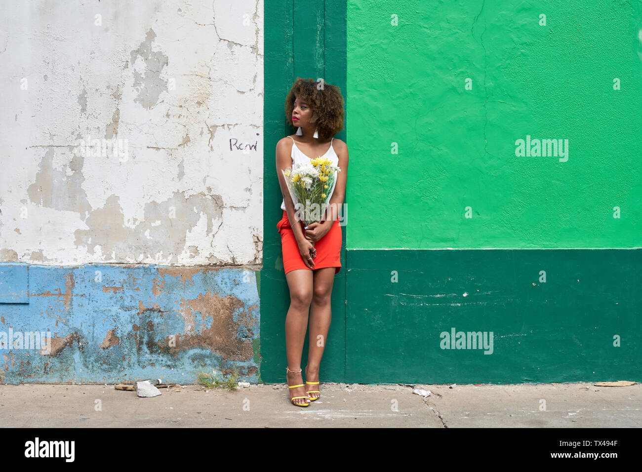 Junge Frau mit Blumen lehnte sich gegen die Wand suchen araund Stockfoto