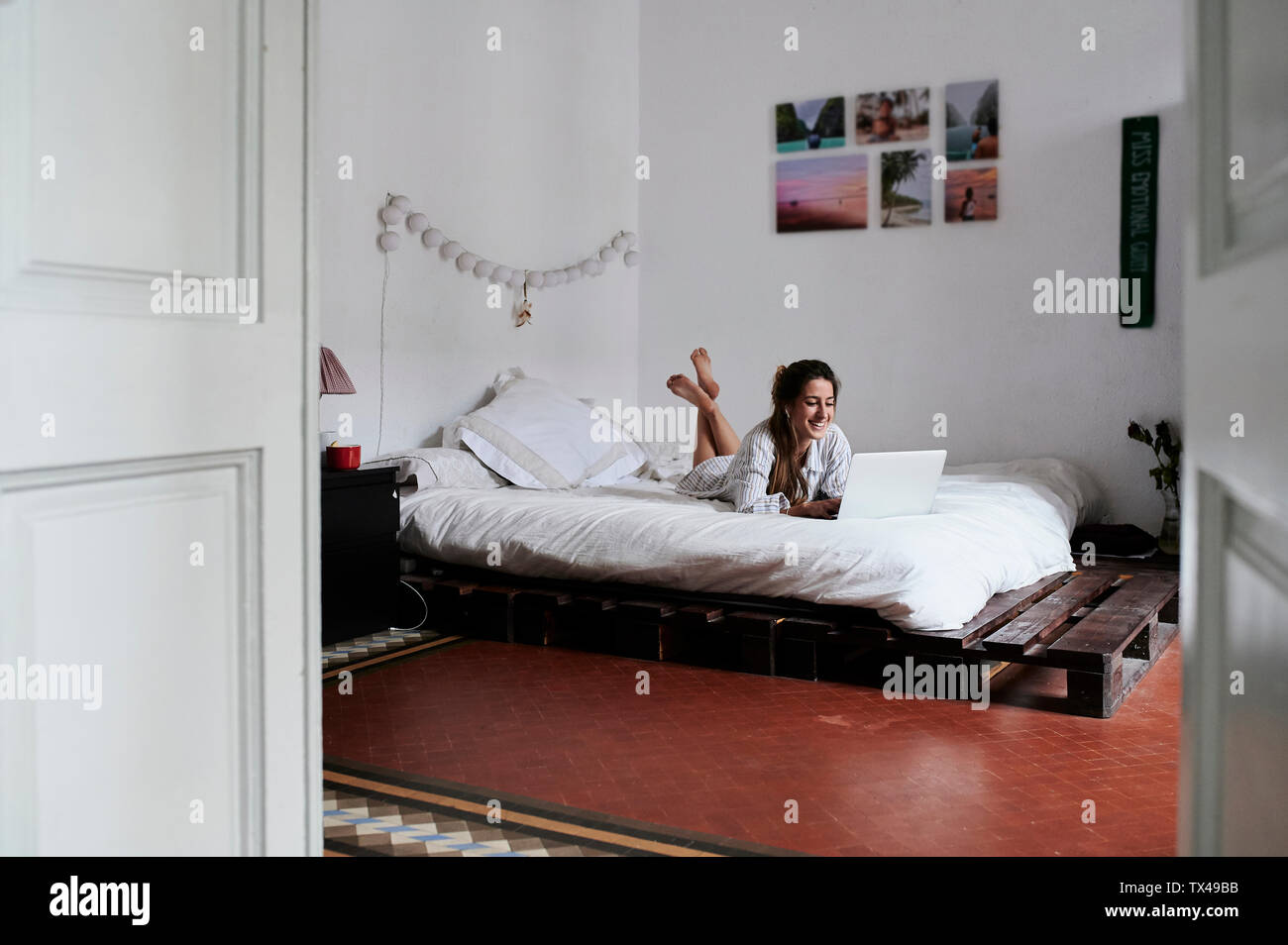 Junge Frau im Bett liegend, mit laptop Stockfoto