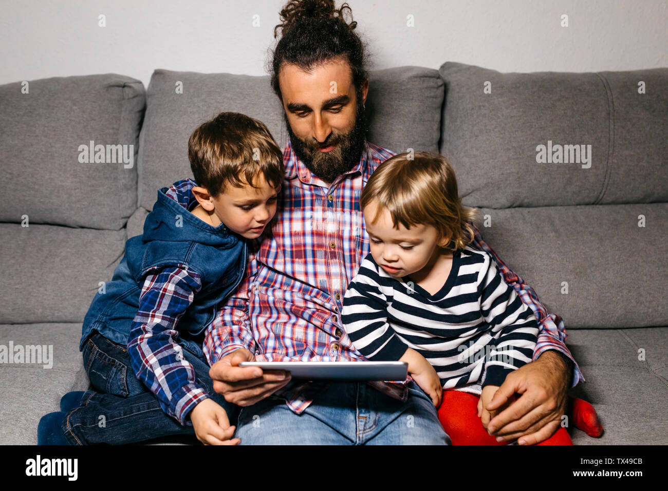 Vater sitzen auf der Couch, mit seinen Kindern Filme auf digitalen Tablet Stockfoto