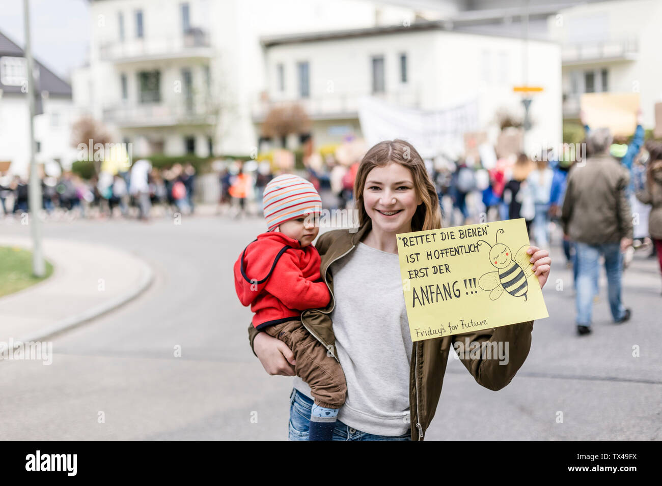 Mädchen mit Baby auf dem Arm hält ein Plakat auf einer Demonstration für den Umweltschutz Stockfoto