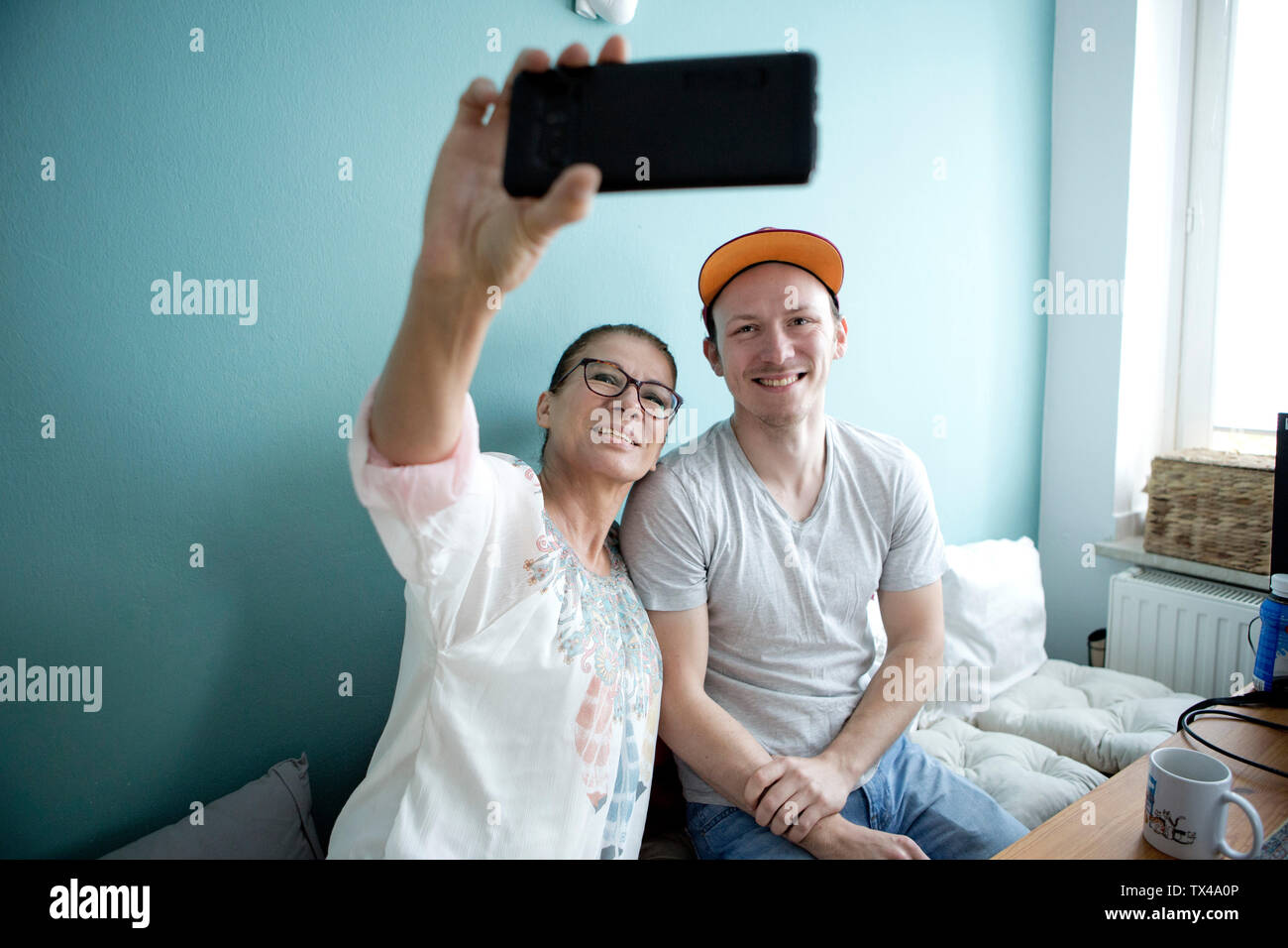 Mutter und Sohn am Küchentisch sitzen, wobei smarrtphone selfies Stockfoto
