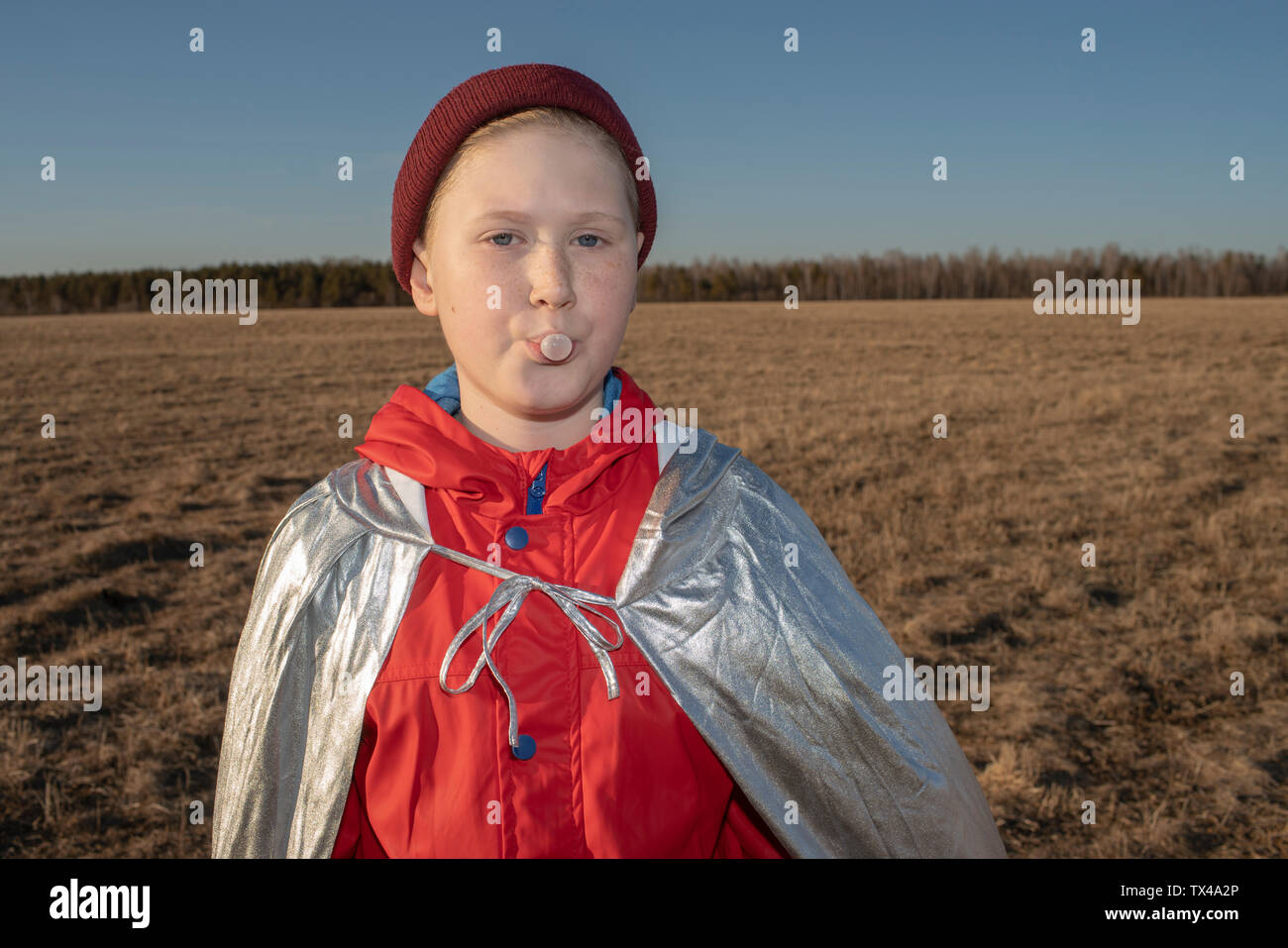 Portrait der Junge verkleidet als Superheld in Steppen Landschaft weht ein Kaugummi bubble Stockfoto