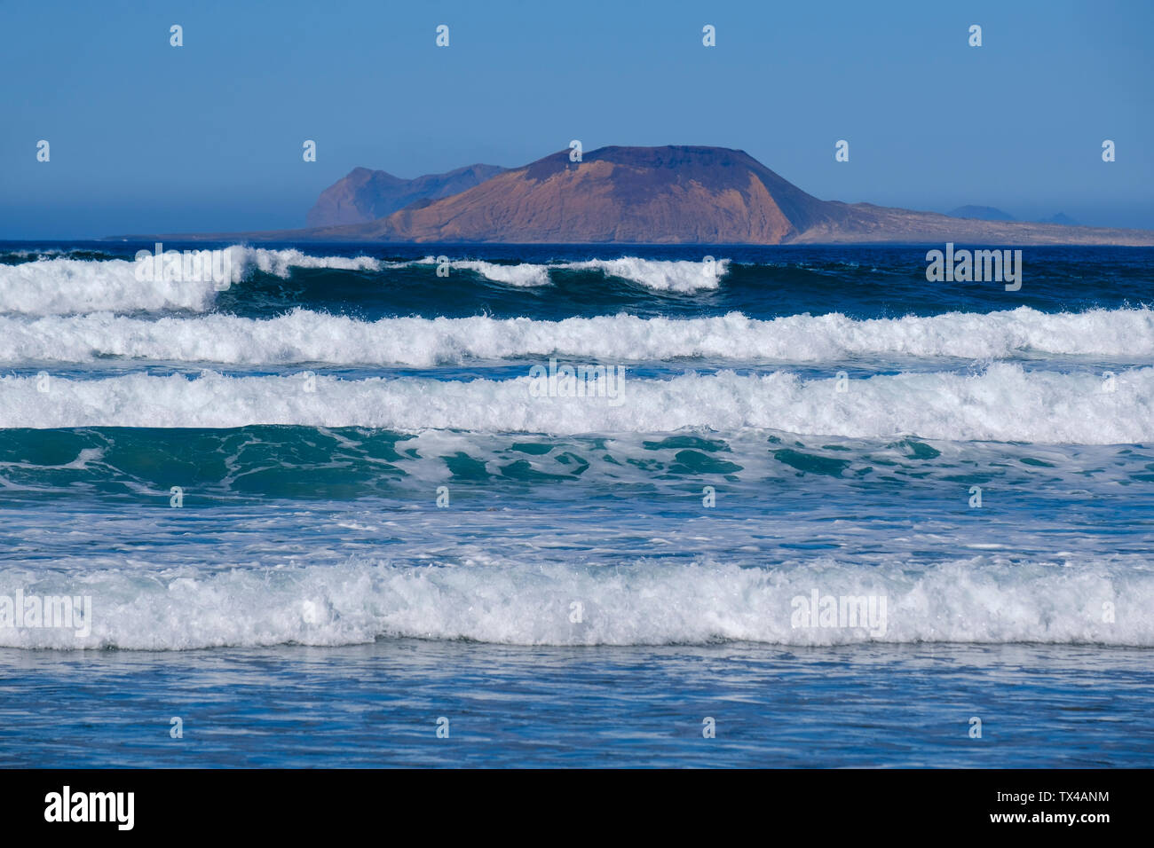 Spanien, Kanarische Inseln, Lanzarote, Caleta de Famara, Wellen, La Graciosa im Hintergrund Stockfoto