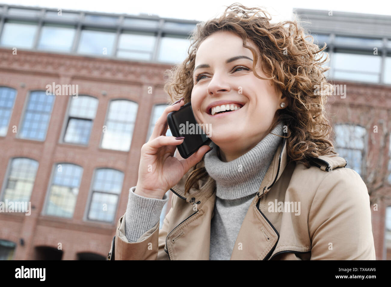 Portrait von Frau mit lockigem Haar auf dem Telefon Stockfoto