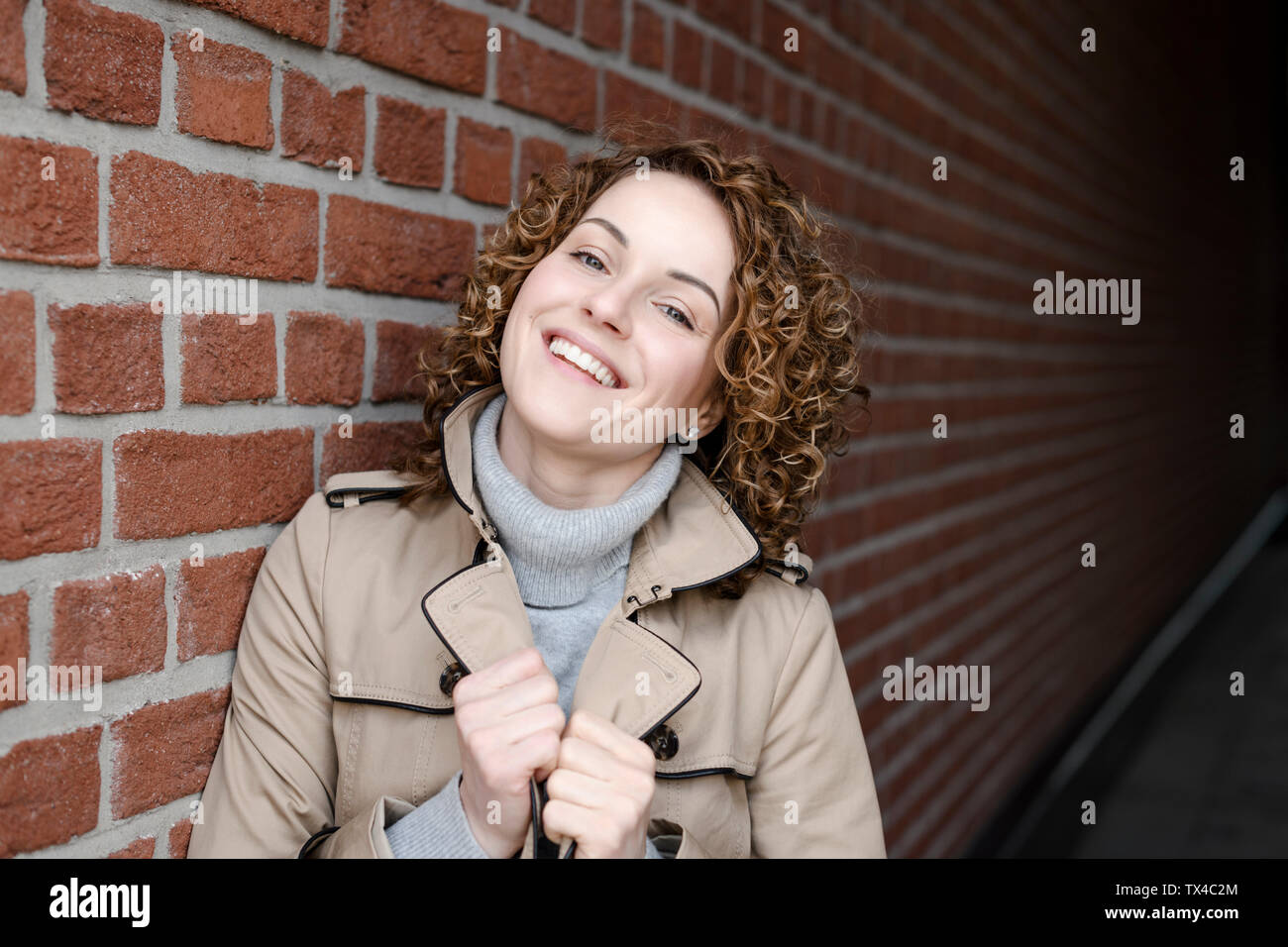 Porträt der lächelnde Frau mit lockigem Haar Trenchcoat und rollkragen pullover Stockfoto