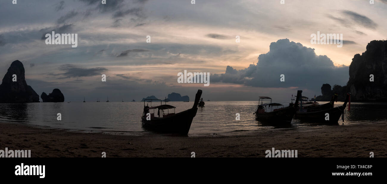 Thailand, Krabi, Railay Beach, Bay mit Long-tail Boote auf dem Wasser schwimmend bei Sonnenuntergang Stockfoto