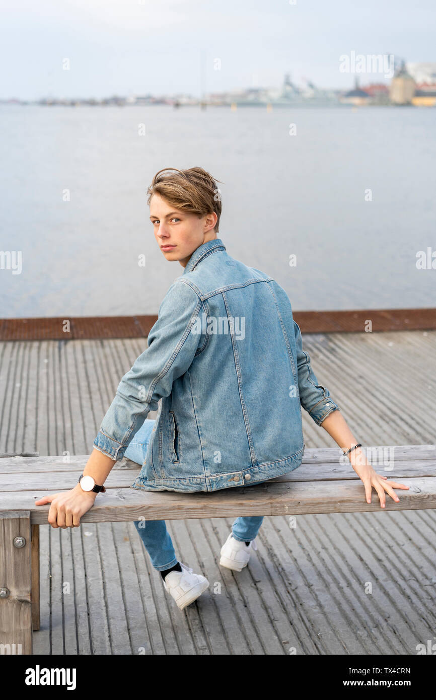 Dänemark, Kopenhagen, jungen Mann sitzen auf einer Bank an der Uferpromenade Stockfoto