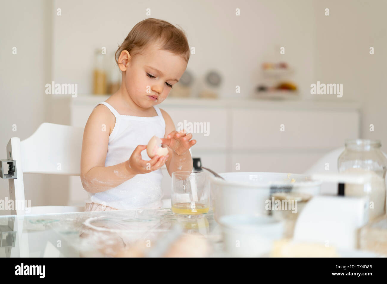 Mädchen, die einen Kuchen in der Küche zu Hause knacken ein Ei Stockfoto