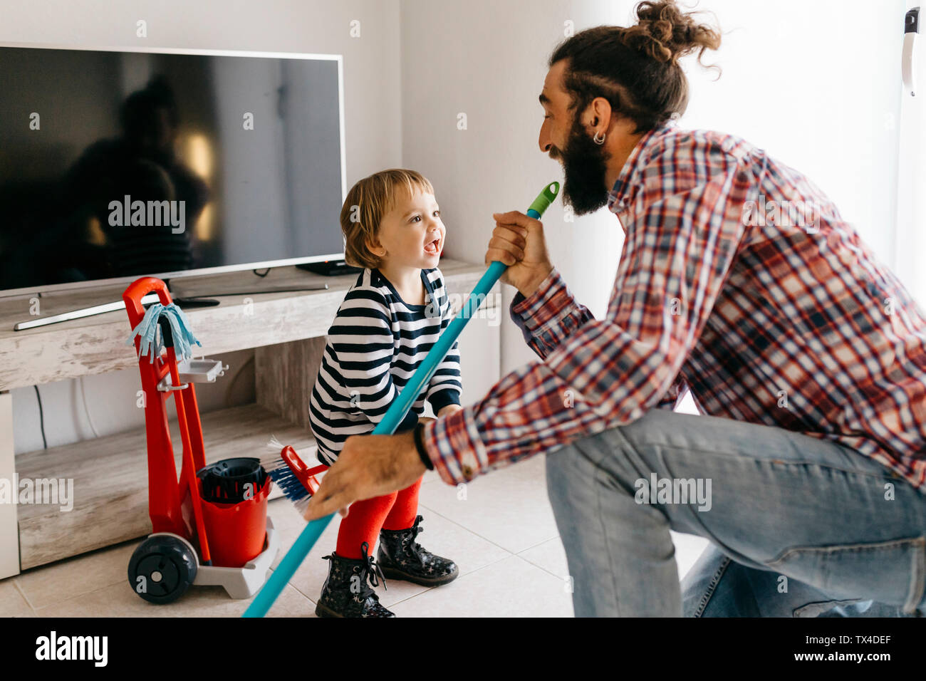 Vater und Tochter Spaß zusammen während der Reinigung der Wohnzimmer Stockfoto