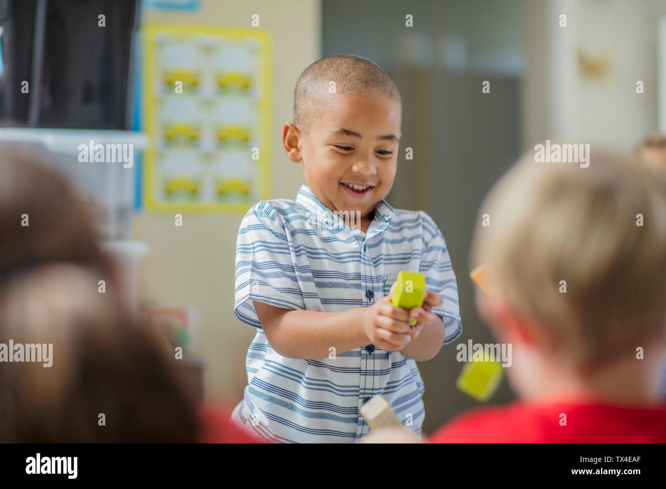 Glückliche junge spielt mit anderen Kindern im Kindergarten Stockfoto
