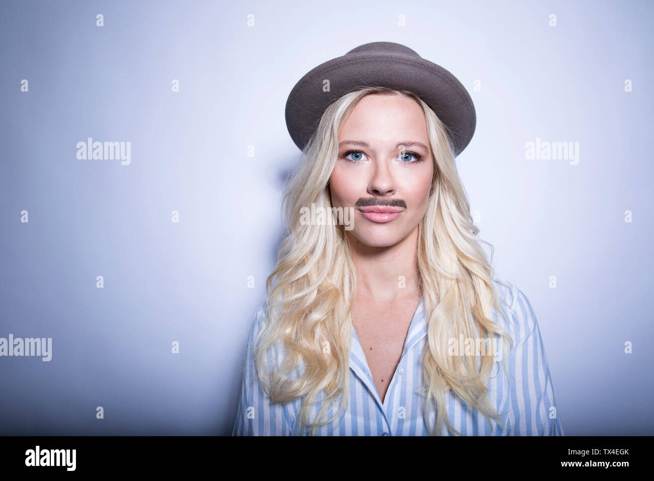 Porträt der blonde junge Frau mit gefälschten Schnurrbart und Hut Stockfoto