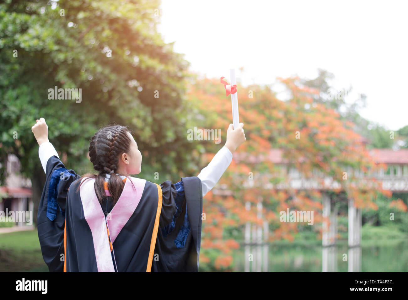 Glücklich und froh, graduierte Asiatische student stehendes Mädchen und zeigt Hand, Glückwünsche, Weiterbildung Erfolg, Konzept Bildung und fertig Lea Stockfoto