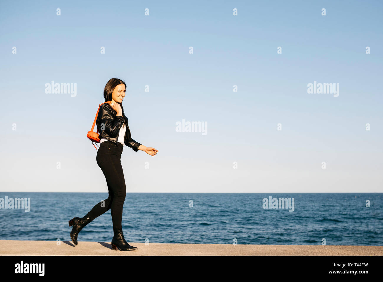 Glückliche Frau mit roten Tasche wandern, das Meer im Hintergrund Stockfoto