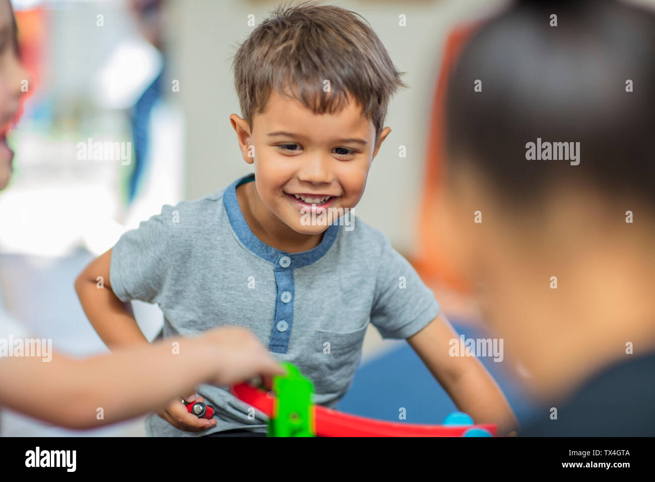 Glückliche junge spielt mit anderen Kindern im Kindergarten Stockfoto