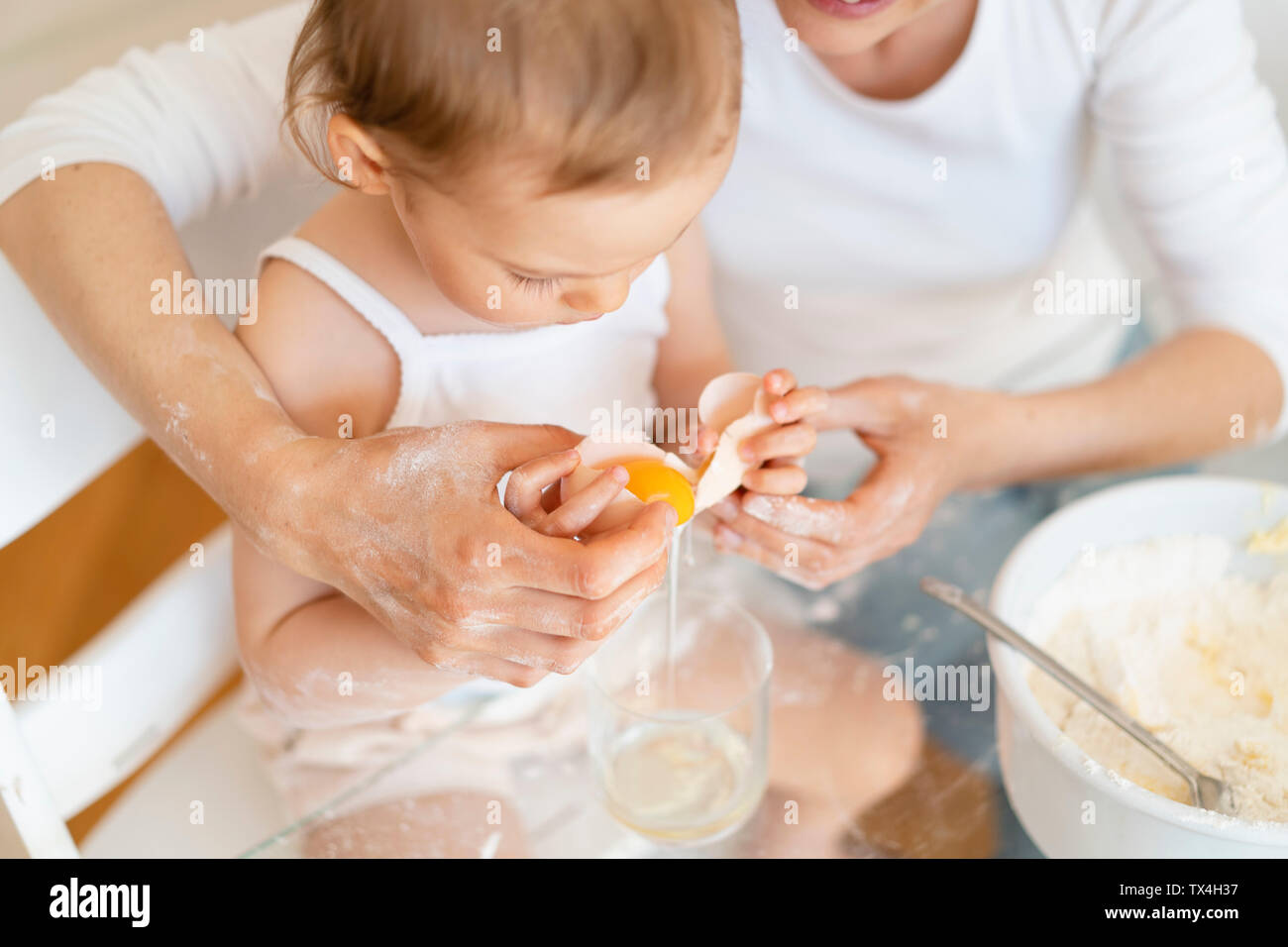 Mutter und Tochter einen Kuchen zusammen in der Küche zu Hause knacken ein Ei Stockfoto