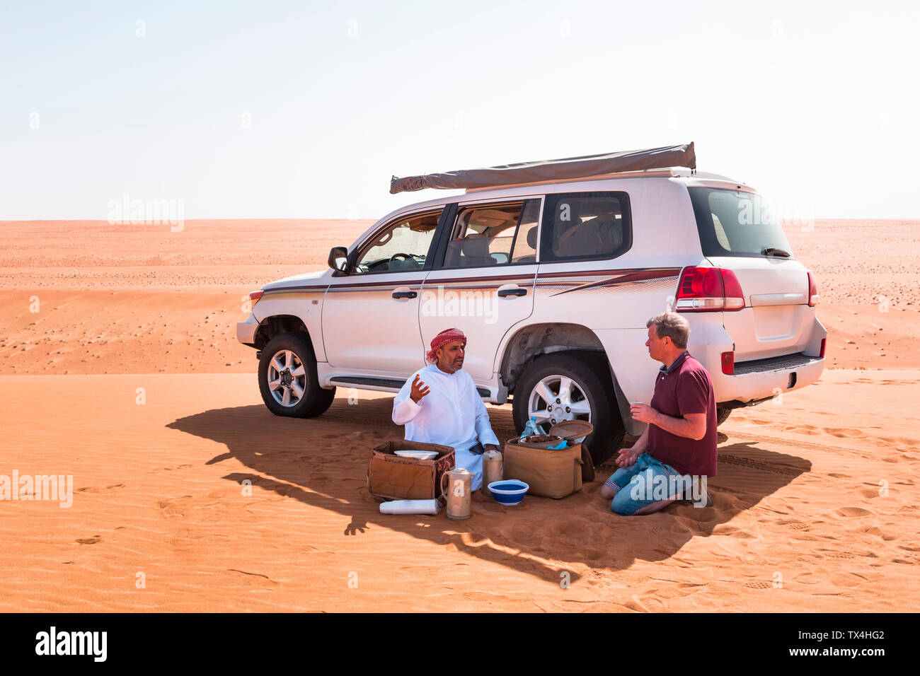 Touristische mit einer Kaffeepause mit seinen lokalen Fahrer in der Wüste Wahiba Sands, Oman Stockfoto