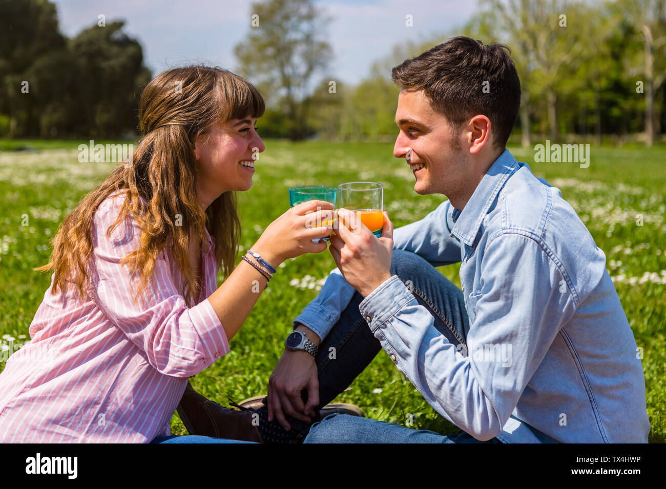 Junges Paar toastin mit Fruchtsaft in einem Park Stockfoto
