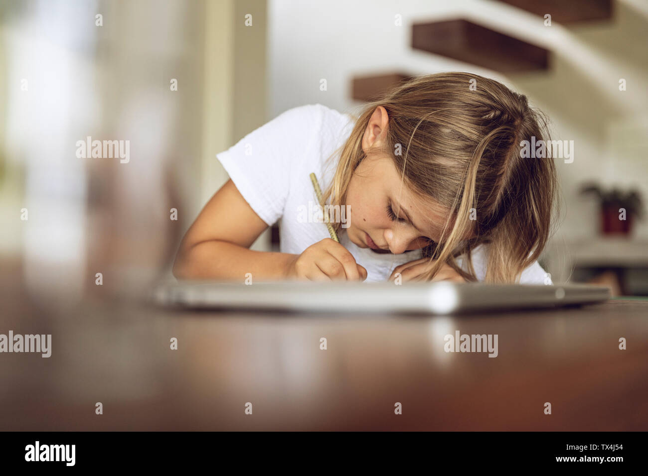 Mädchen Sitzen am Tisch Schreiben in Tagebuch Stockfoto