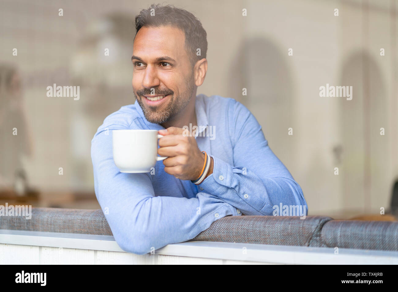 Lächelnd Geschäftsmann mit Tasse Kaffee Blick aus Fenster Stockfoto