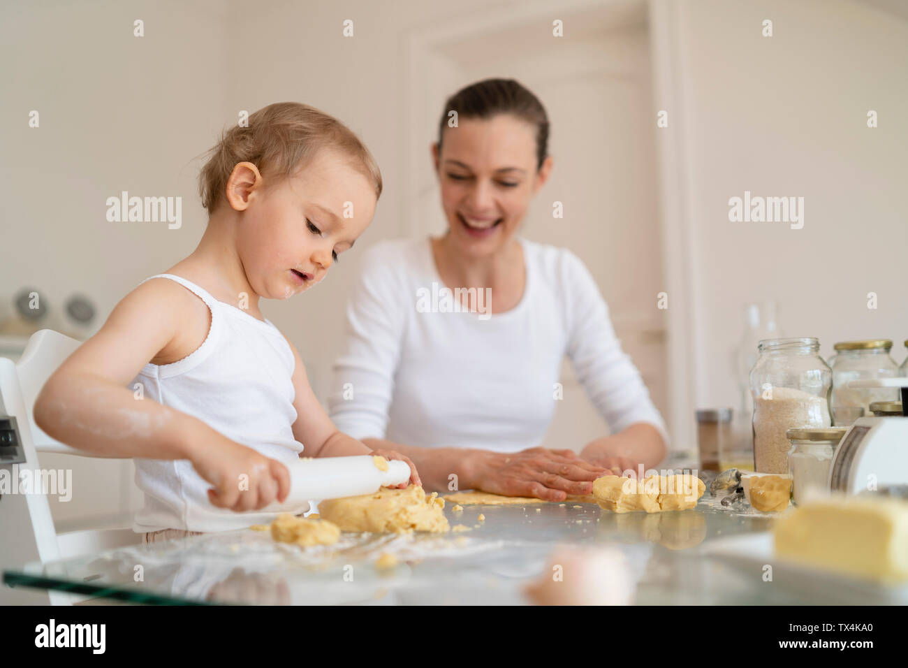 Mutter und Tochter mit Teig rollen einen Kuchen zusammen in der Küche zu Hause. Stockfoto
