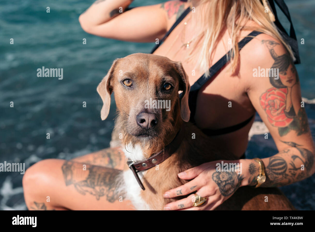 Spanien, Mallorca, Porträt der Hund sitzt neben tätowierte Frau am Meer. Stockfoto