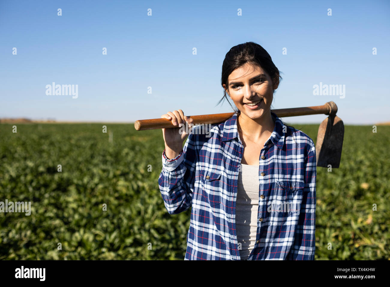 Junge Frau Bauer mit Hacke auf dem Feld Stockfoto