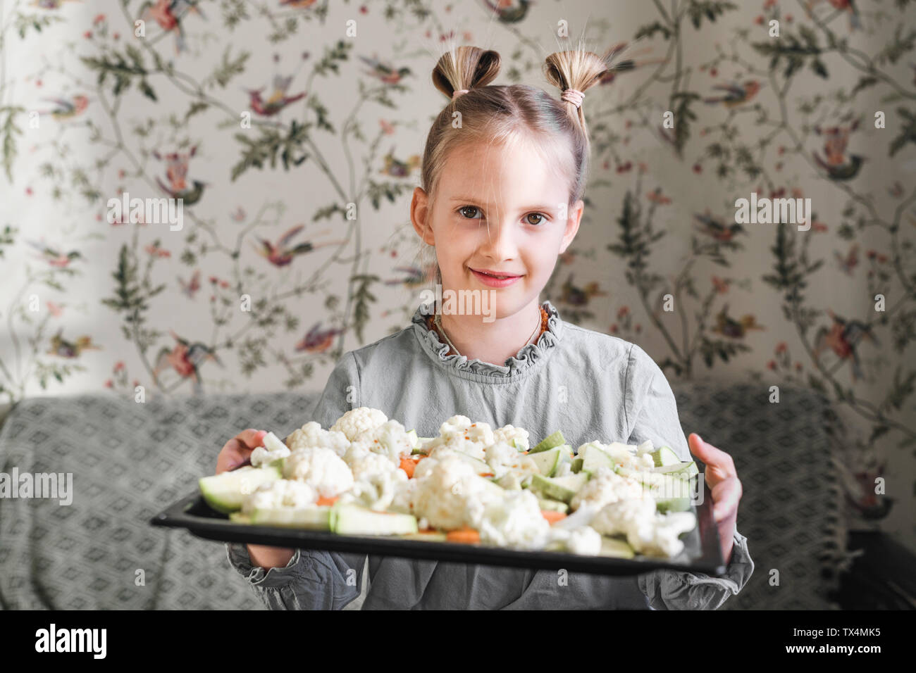 Portrait von blonde Mädchen mit backblech von rohem Gemüse Stockfoto