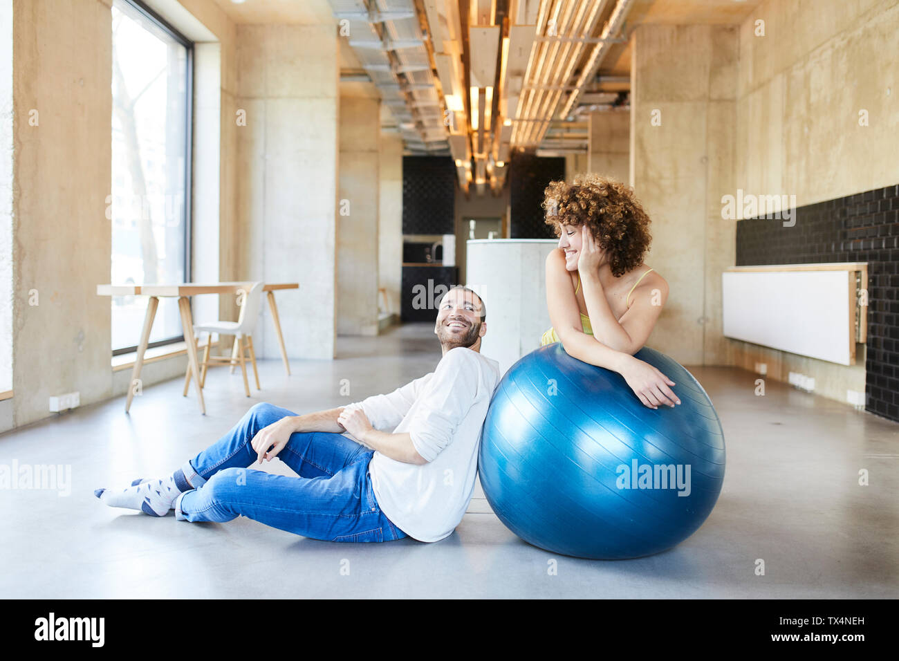 Lächelnd Mann und Frau mit Fitness Ball in modernen Büro Stockfoto