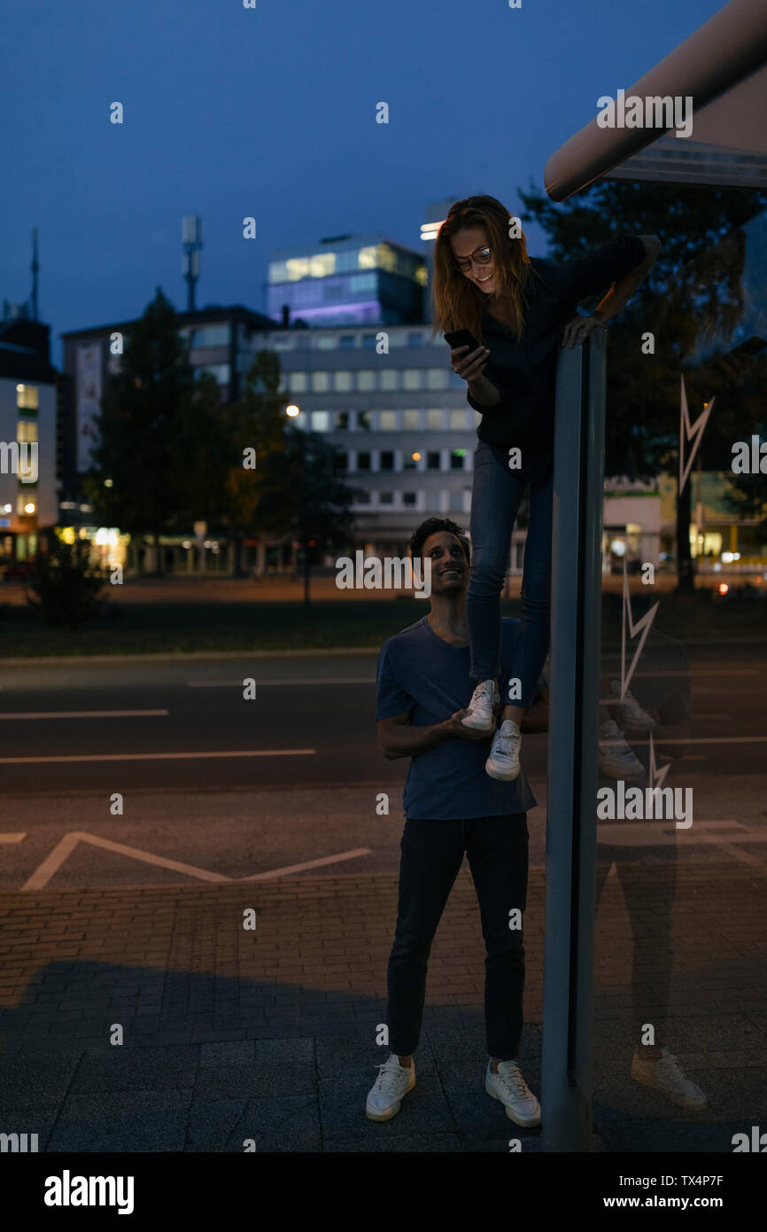 Junger Mann, Freundin mit Handy ein Bein in der Stadt bei Nacht Stockfoto