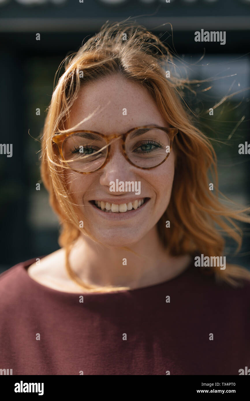 Porträt der glückliche junge Frau mit Brille und windgepeitschten Haar Stockfoto